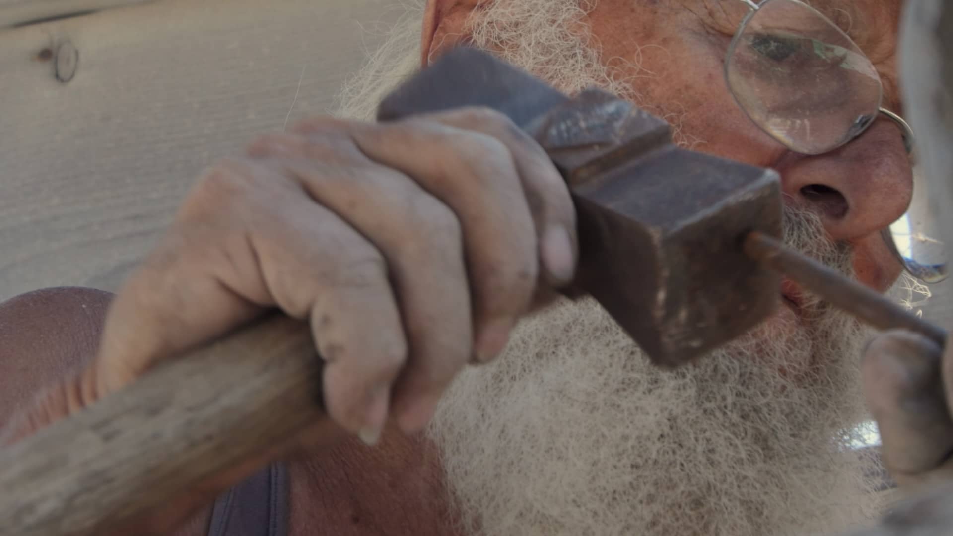 La main de l’artiste : Michalis Kassis en pleine création Michalis Kassis travaillant avec un marteau et un burin.