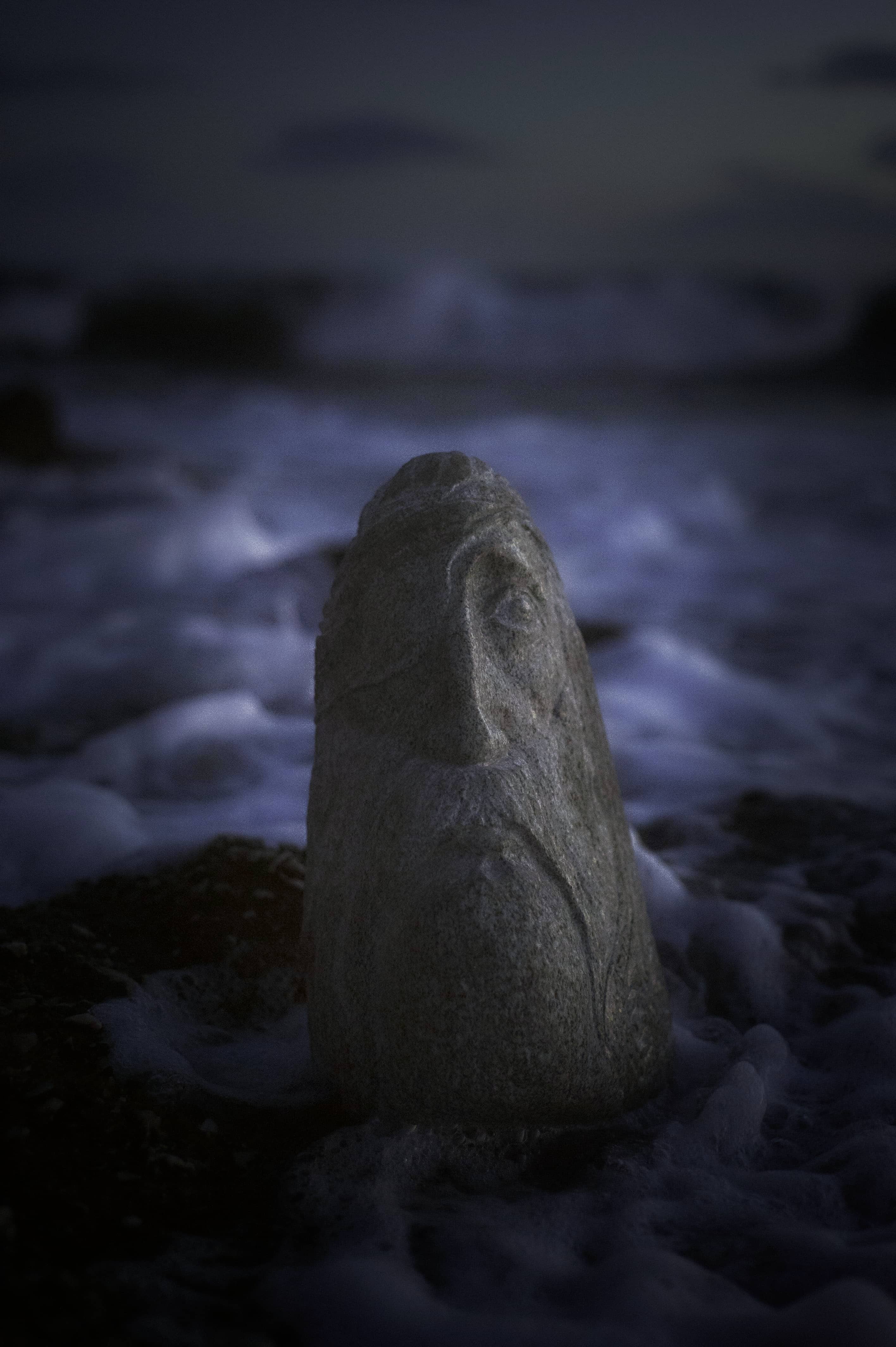 Sculpture éphémère au crépuscule Sculpture représentant un visage émergeant de l'eau au crépuscule.