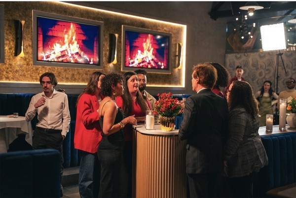 keepers-of-the-door-08 A group of guests chat while standing near the bar, under the restaurant’s fireplace screens.